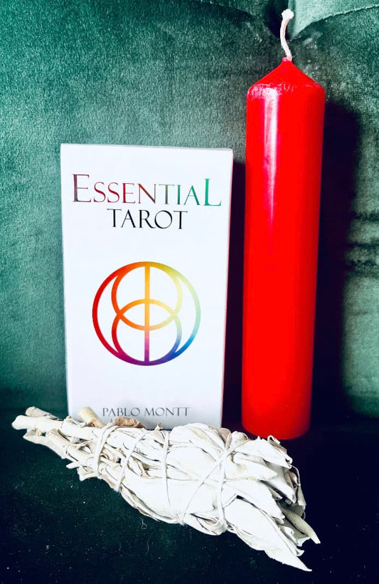 Photo of a boxed set of Essential Tarot by Pablon Montt against a green background with a large red candle next to it.