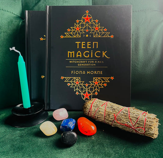 Photo of the Book of Teen Magic: Witchcraft for a New Generation by Fiona Horne with a small green candle, crystals and a smudge stick at the front of the camera.