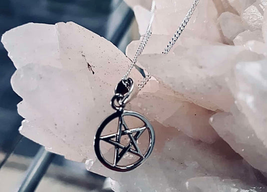 Photo of a sterling silver pendant with a pentagram charm, sitting atop a large stone.