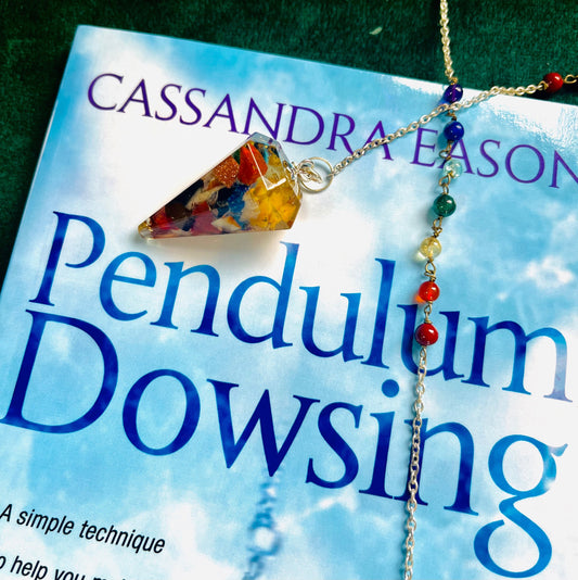 Photo of an orgone pendulum on top of the book Pendulum Dowsing.