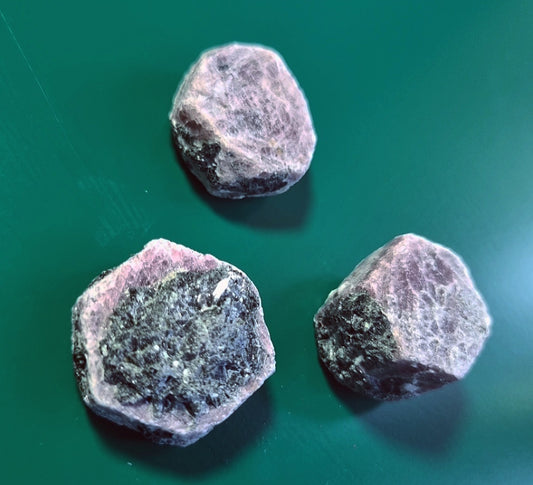 Photo of three rough ruby stones.