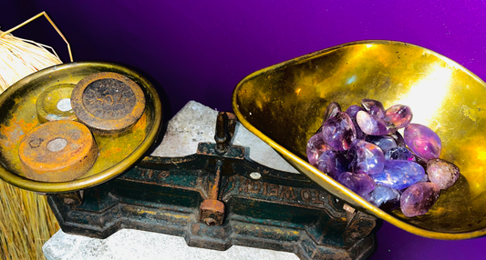 Several ametrine tumblestones sitting in some old fashioned weighing scales.