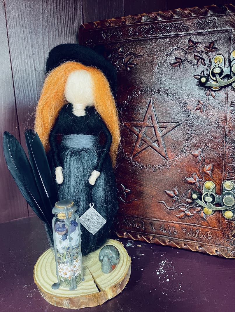 Photo of a handmade felt witch with orange hair in black robe with grey sash..