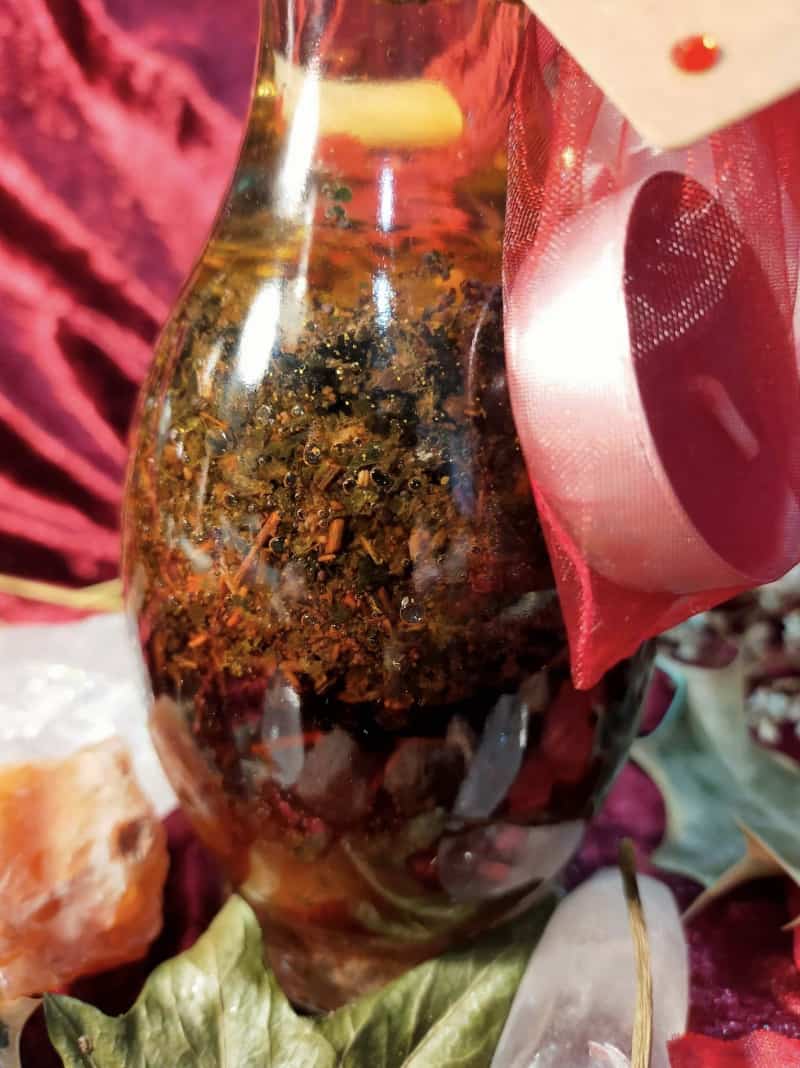 Image of a bottle of bath oil containing herbs and flowers.