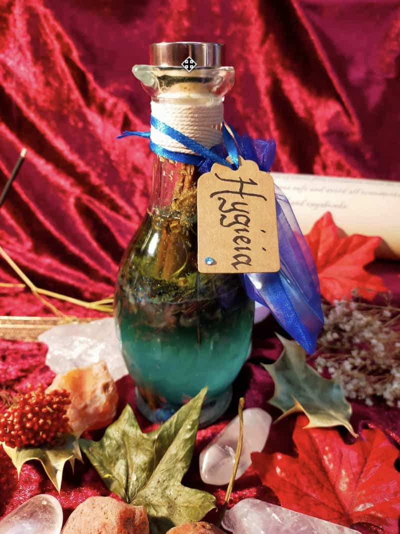 Image of a bottle of bath oil labelled Hygieia and containing herbs and flowers.