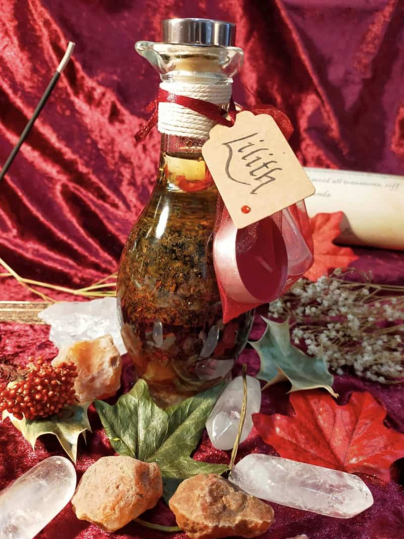 Image of a bottle of bath oil labelled Lilith, containing herbs and flowers.