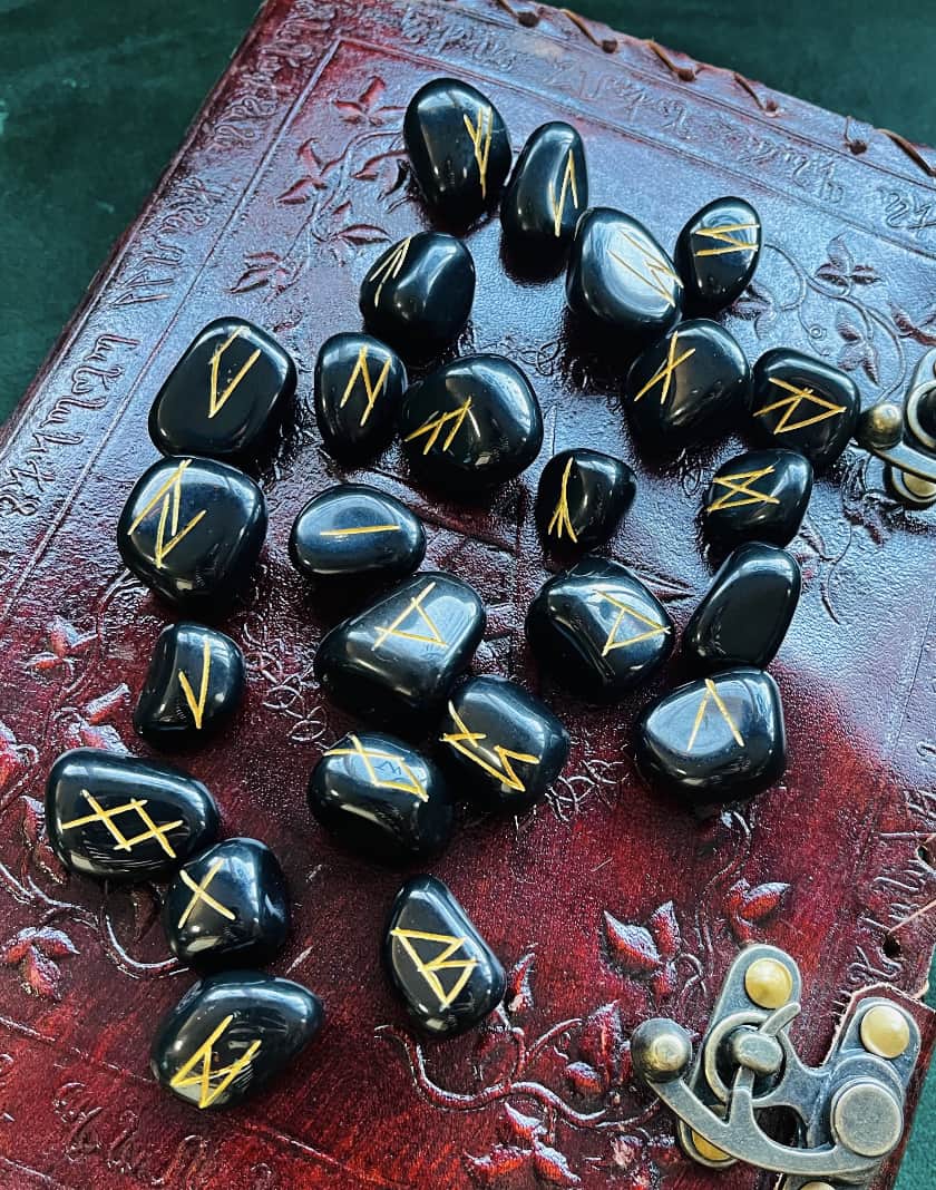 Photo of a set of black jasper runes resting on a leather journal.