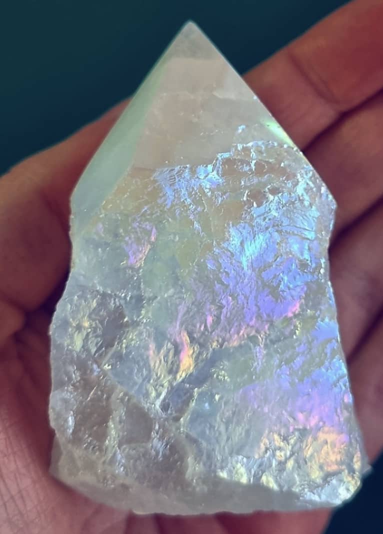 Photo of a snow aura quartz polished point in a palm for size reference.