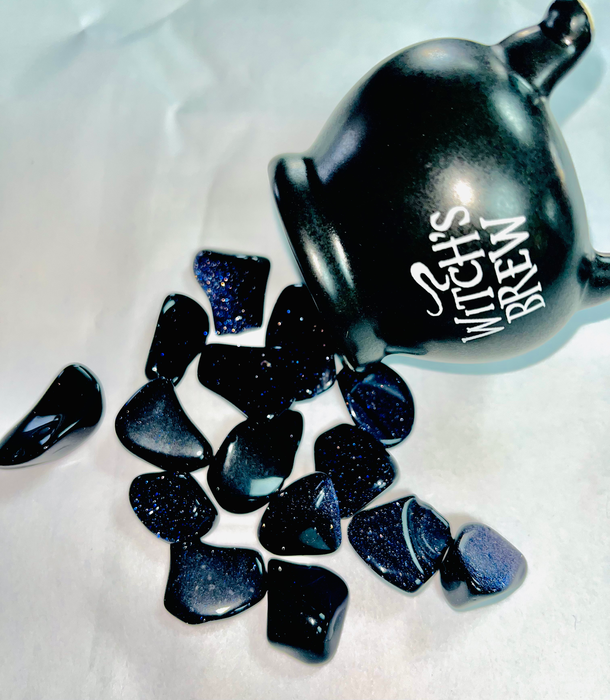 Photo of a number of small star stones spilling out from a miniature witch's cauldron.