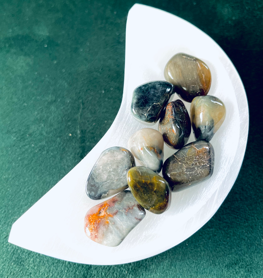 Photo of a cresent shaped selenite dish with a number of chrysoberyl stones in.