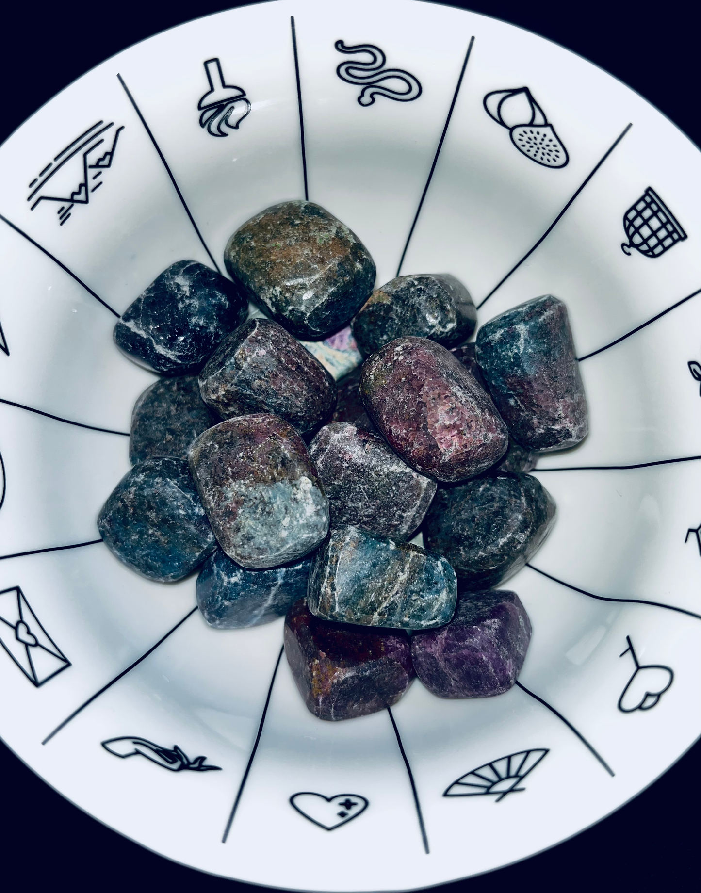 Photo of several ruby in zoisite stones in a white patterned bowl.