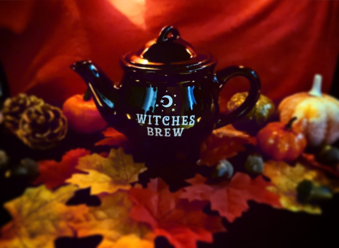 Photo of a black cauldron-shaped teapot with white text saying "Witches Brew"