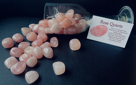 Photo shows a number of rose quartz tumblestones spilling out from a glass.