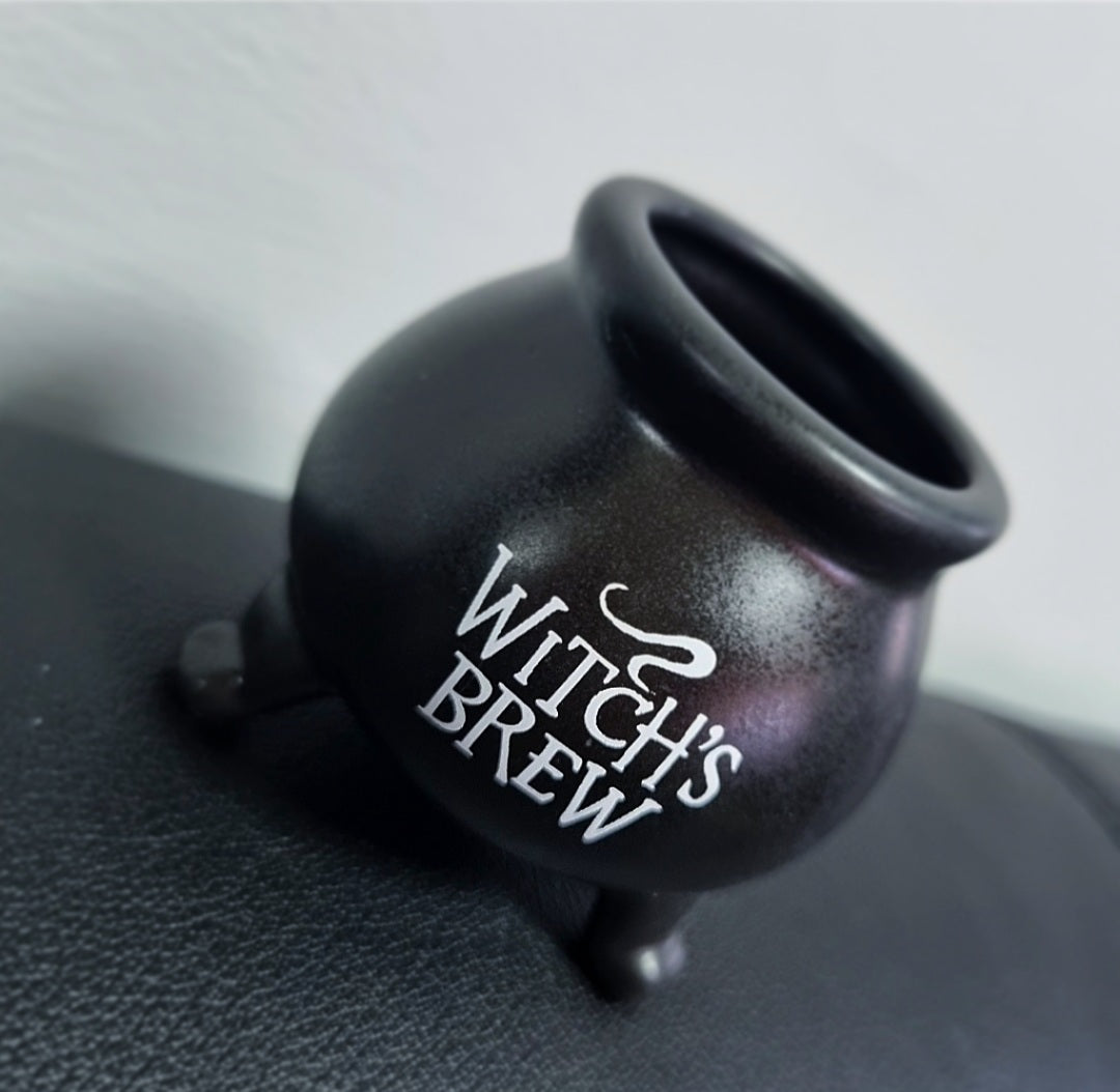 Photo of a small black cauldron shaped pot with the words 'Witch's Brew' in white