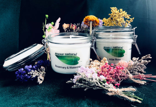 Photo of two mason jar candles - one rosemary & watermint, one attar rose - surrounded by dried flowers.