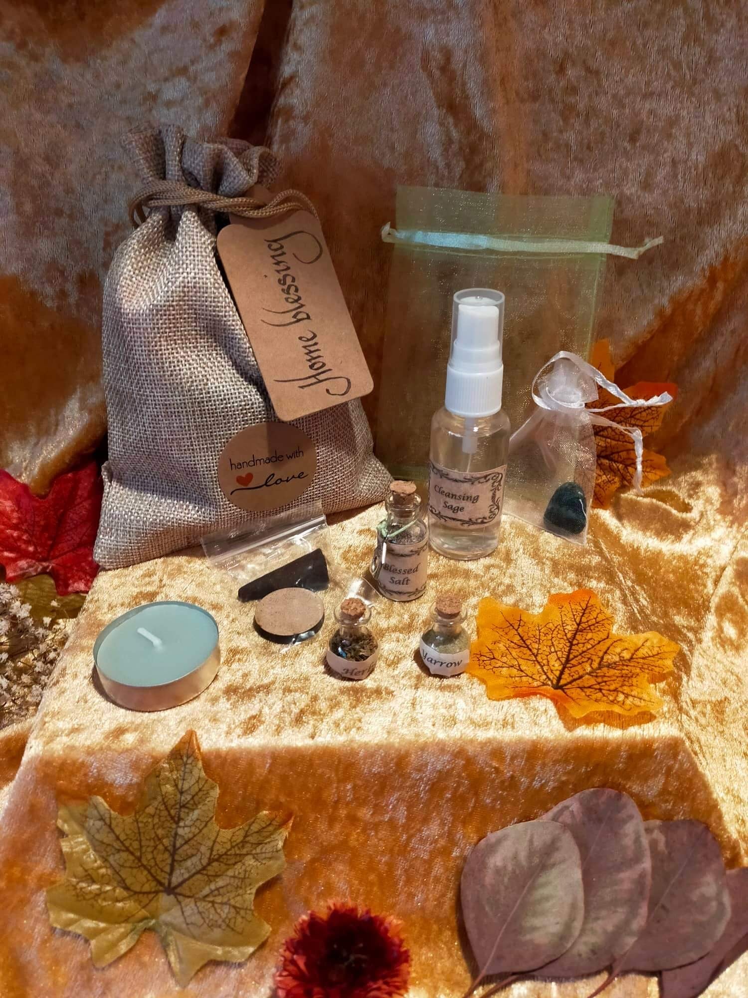 Photo of a spell bag with the various items included also shown in the photo, including crystals, salt and cleansing spray.