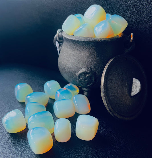 Photo shows a number of opalite tumblestones in and around a small witch cauldron.